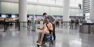 Woman in a wheelchair assisted by staff